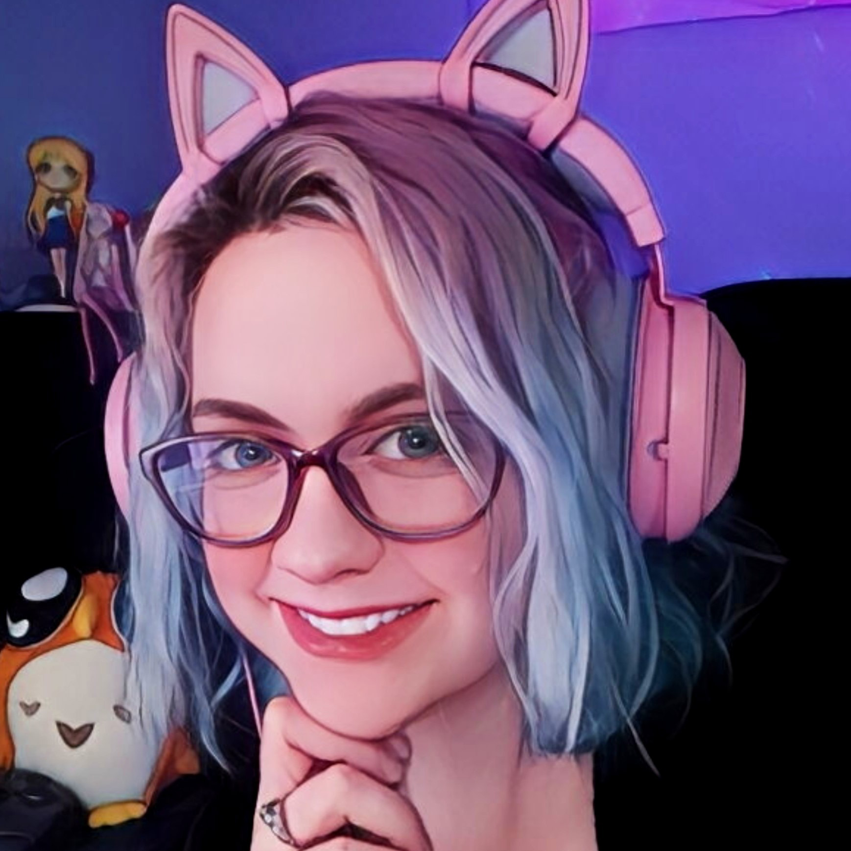 Headshot of Ashley Phipps. She is wearing pink headphones with decorative cat ears on them and several plushies are in the background.