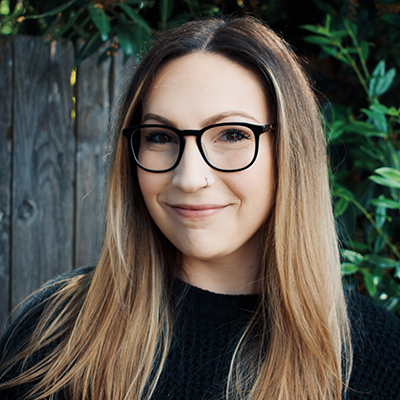 Headshot of Taylor McElroy in front of a dark fence and trees.